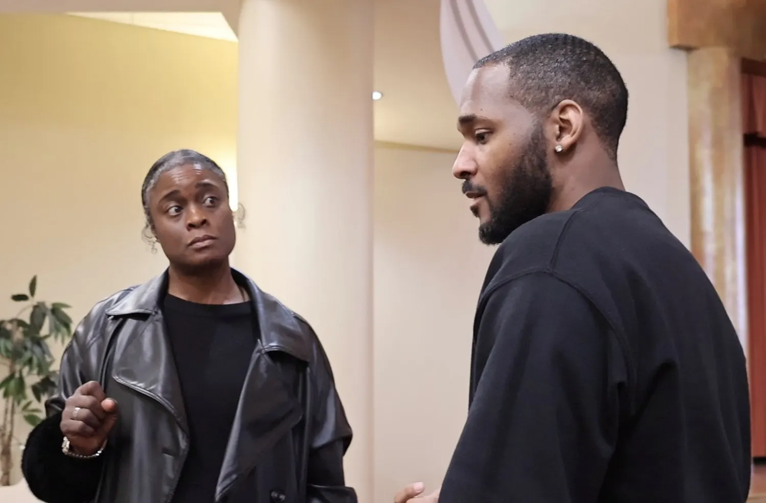 Standing in conversation with a client, both listening, mid-discussion.