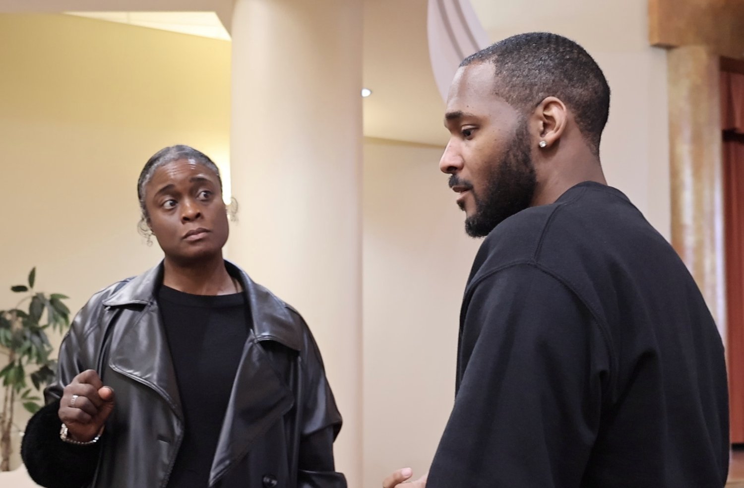 Standing in conversation with a client, both listening, mid-discussion.