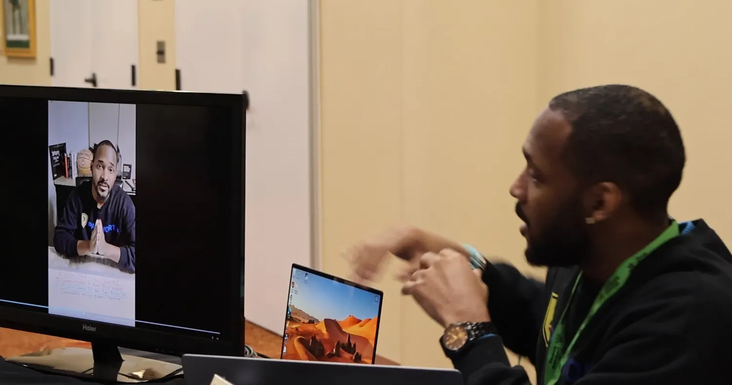 At the desk, his own recorded material playing on the monitor alongside.