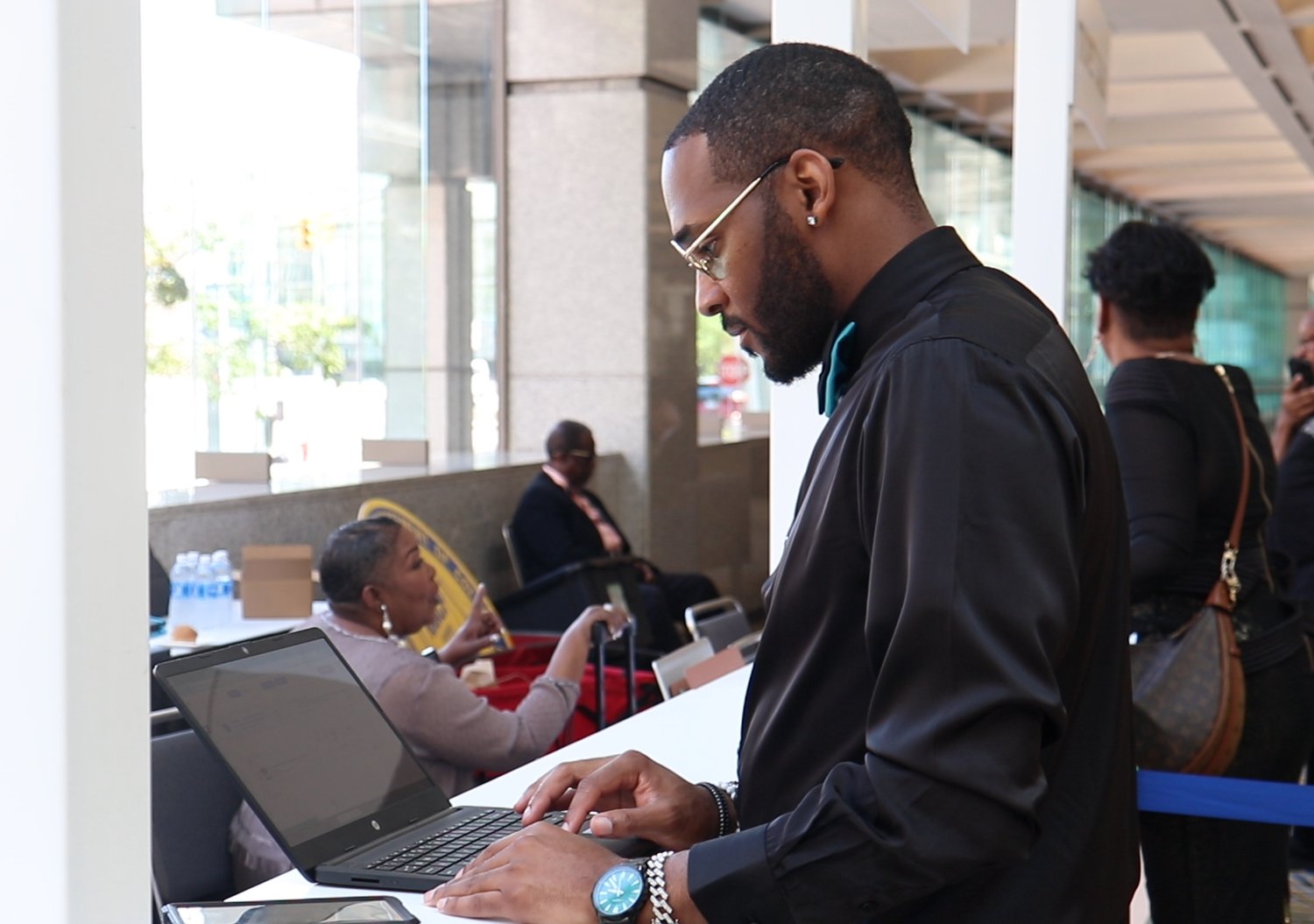 Working a laptop on site during an event build-out, in a glass concourse.