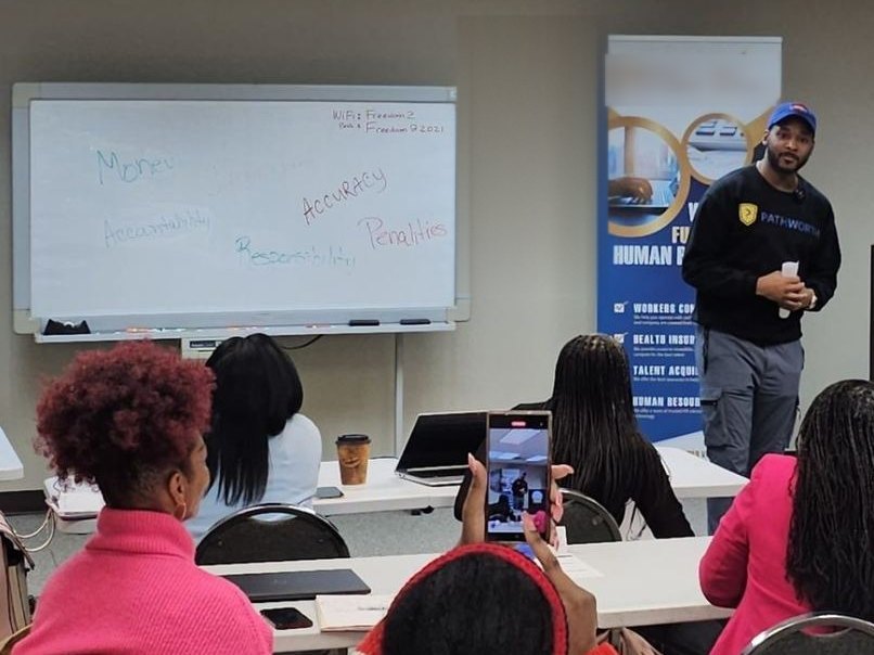 Teaching a working session to a full room, whiteboard behind, Pathworth on the jacket.